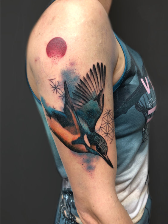 Kingfisher tattoo on an upper arm with geometric background