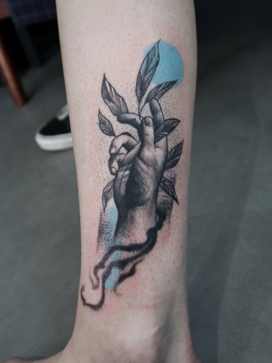 Hand tattoo in black and grey with blue on leg