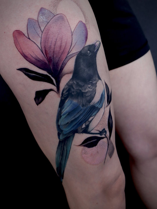 tattoo of a magpie and magnolia flower on a thigh